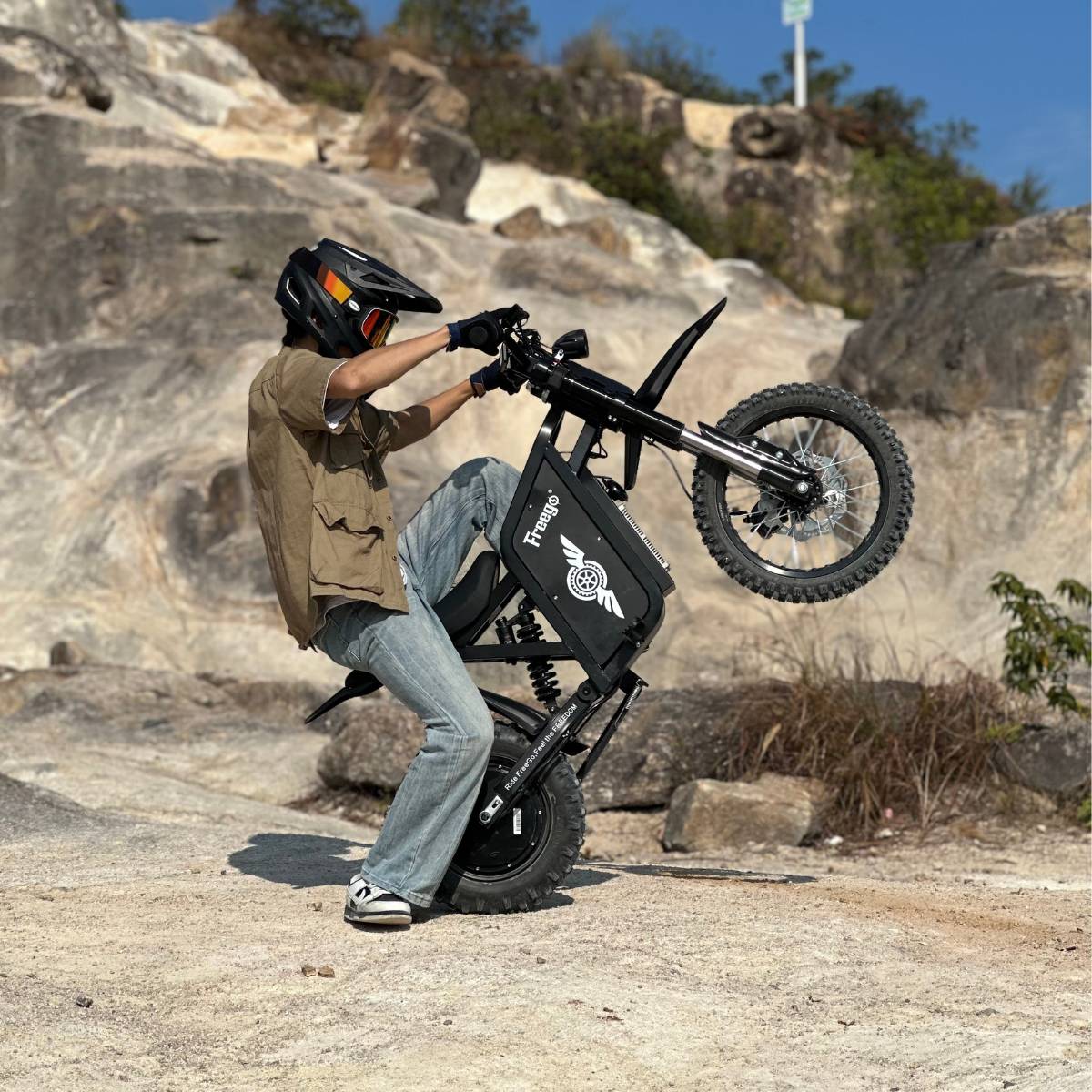 Rider performing a wheelie on Freego X0 electric bike in rocky outdoor terrain, showcasing off-road power.
