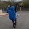 Person in a blue hoodie performing a wheelie on bicycle in an outdoor setting.